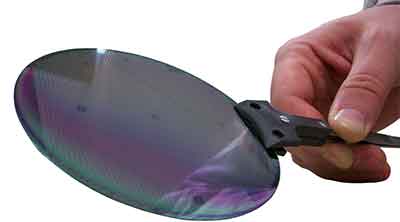 researcher holding silicon wafer in wand